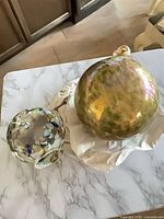 Both glass orbs side by side on table for size comparison