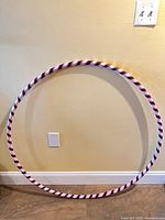 Full view of hula hoop against wall showing striped pattern and size perspective