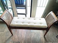 Full view of bench showing cane sides, cushion, wood frame