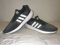 Side view of both shoes displaying three white stripes and overall condition