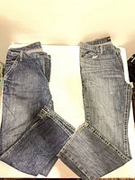 Both pairs of Ariat FR jeans laid flat showing front and leg wash contrast