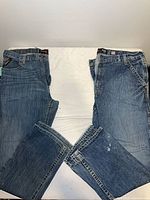 Two pairs of Ariat jeans laid flat