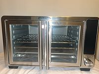 Front view of stainless Gourmia XL countertop oven with dual glass doors closed