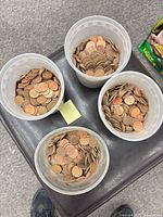 Four cups filled with pennies on a stool