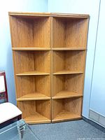 Front view of both triangular corner bookcases showing shelves and overall condition