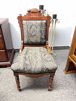 Full view of chair front showing upholstery, carving, legs and one caster