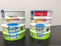 Two unopened multi-packs of Playtex Diaper Genie refills on table
