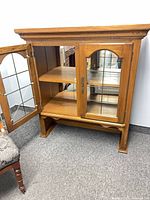 Front view of wooden display hutch with mirrored interior and glass doors
