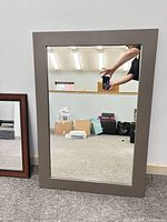 Front view of grey framed mirror leaning against wall
