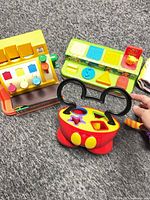 All toys laid out showing cash register, pop-up toy, shape sorter, plush monster, fabric books