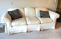 Front view of cream jacquard sofa showing three cushions, rolled arms and skirt