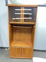 Front view showing top glass doors, open TV compartment, bottom doors