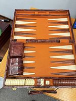 Open faux-leather backgammon case showing board, checkers, dice cups, dice, doubling cube
