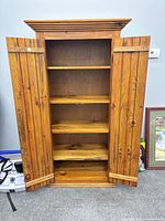 Full view of wooden wardrobe with doors open showing shelves