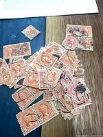 Pile of orange-rose 9¢ Jefferson stamps with cancellations on wood surface