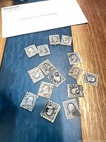 All 16 blue 1-cent Benjamin Franklin stamps spread on table with envelope visible