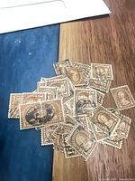 Pile of cancelled yellow-brown 4¢ Martha Washington stamps on wood surface