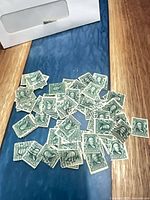 Pile of green 1¢ Ben Franklin stamps spread on table