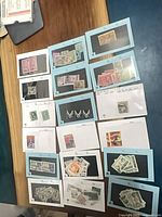 Overview showing 16 dealer cards each holding multiple Canadian and U.S. stamps