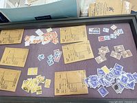 Overall view of frame with assorted stamps sorted in groups alongside payroll envelopes