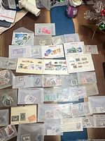 Overview of numerous envelopes and display cards containing assorted stamps spread on table