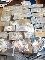 Overview of numerous glassine envelopes laid out, each containing mixed world stamps