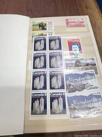 Album page showing $0.50 candle block, $1 red definitive, block of Canada 8¢ candles, $0.50 portrait stamp, skyline se-tenant pairs