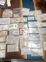 Overview of numerous envelopes and bags of used stamps spread on table