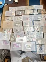 Overview of numerous clear sleeves each holding several postage stamps spread on table