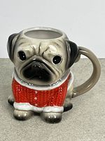 Side angled view of entire pug mug showing handle and red sweater design