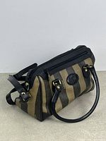 Three-quarter view of handbag showing stripes, leather trim and handles