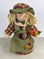 Front view of scarecrow showing clothing, straw hair and carrot accessory