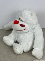 Front angled view of white yeti plush showing red heart nose and cheek