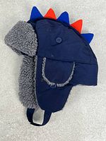 Left side view of navy trapper hat with grey sherpa lining and blue/red spikes