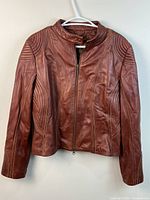 Front view of brown leather jacket on hanger