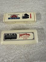 Two cream plastic harmonica cases labelled Big River Band and Marine Band