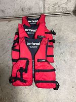 Three stacked red Airhead life vests front view