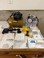 Overall lot showing both cameras, lenses, accessories, manuals and packaging