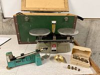 Two scales, weight box, scoop, and wooden case displayed