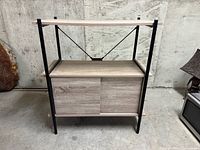 Front view of shelving unit showing metal frame, top shelf, sliding door cabinet closed on left side, open on right