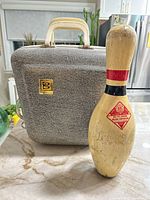Front view of Brunswick bowling bag and wooden bowling pin