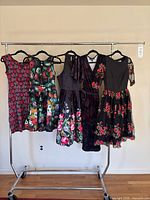 Front view of all five floral dresses on garment rack
