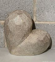 Front view of silver textured heart figurine against block wall