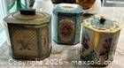 Three vintage floral turquoise metal tins with lids and black knobs displayed together
