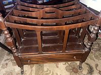 Full view of wooden magazine rack showing slotted panels, drawer, and casters