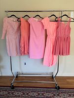 Front view of all five pink dresses on rack