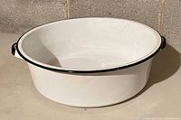 White enamelware tub with black rim and handles