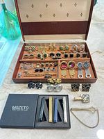 Full lot showing jewelry box open with cufflinks, tie bars inside, additional cufflinks and Mozeto tie bars positioned in front