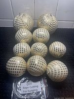 ten fabric-wrapped balls and packet of cord on surface