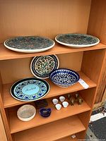 Shelf with two large geometric platters top, three assorted plates and bowl middle